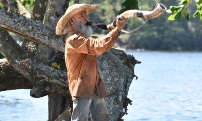 O ator Osmar Prado como Velho do Rio no Pantanal;  ele está em pé, de lado, tocando o berrante